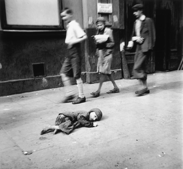  Ein hilfloser Junge liegt auf dem Pflaster im Warschauer Ghetto.  Kinder gehen vorbei ... 
